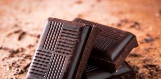 7 Bienfaits Prouvés du Chocolat Noir pour la Santé Carrés de chocolat noir posés sur une surface saupoudrée de cacao