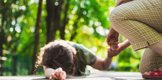 Épilepsie : Causes, symptômes et traitement Enfant pendant une crise d'épilepsie recevant de l'aide d'un adulte dans un parc