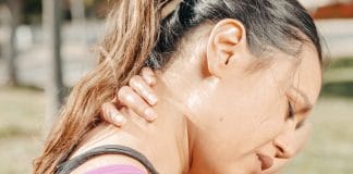 Myalgie (Douleur Musculaire) : Causes et Soulagement Jeune femme massant son cou douloureux à l'extérieur, illustrant les symptômes de la myalgie cervicale - douleur musculaire