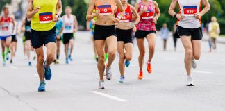 Entraînement au Semi-Marathon pour Tous les Niveaux Coureurs participant à une course de marathon sur une route, portant des dossards numérotés, en pleine action avec des vêtements de sport colorés.