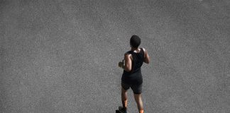 Entraînement au Semi-Marathon : Avancé Coureur en tenue noire et chaussettes orange s'entraînant sur asphalte, préparation pour semi-marathon