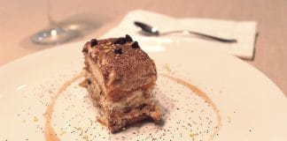 Recette Facile de Tiramisu aux spéculoos Portion de tiramisu maison servi sur assiette blanche avec décoration de cacao et sauce caramel, dessert italien élégant