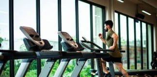 Tout ce qu’il faut savoir sur la VO₂ Max Homme sportif courant sur un tapis roulant dans une salle de sport moderne avec de grandes fenêtres, test de VO₂ max sur équipement Assault Fitness