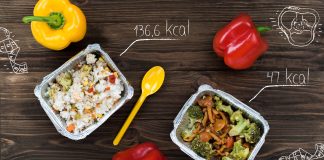 Combien de calories devriez-vous consommer par jour ? Vue aérienne de repas diététiques dans des barquettes en aluminium avec du riz aux légumes et des brocolis aux champignons, accompagnés de poivrons rouges et jaunes frais, avec indication des calories