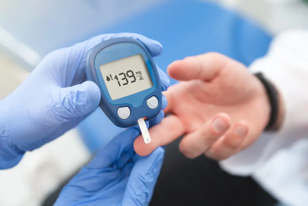 Un professionnel de santé portant des gants bleus effectue un test de glycémie sur un patient à l'aide d'un glucomètre numérique affichant une valeur de 139 mg/dL. Ce test est essentiel pour le suivi et la gestion du diabète.