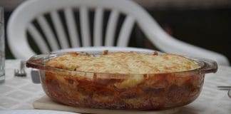 Lasagne aux épinards et béchamel Lasagne aux épinards et trois fromages servie dans un plat en verre transparent sur une table dressée, croûte dorée et couches visibles, ambiance déjeuner en famille