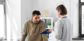 Jaunisse : Ce que c’est, Symptômes, Causes et Traitement Un patient inquiet consulte une médecin qui tient un dossier médical, possiblement pour discuter des symptômes de la jaunisse dans un cabinet médical