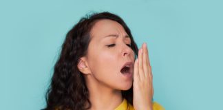 Mauvaise haleine : causes, symptômes et traitements efficaces Femme vérifiant sa mauvaise haleine en soufflant dans sa main, illustrant les préoccupations liées à l'halitose sur fond bleu