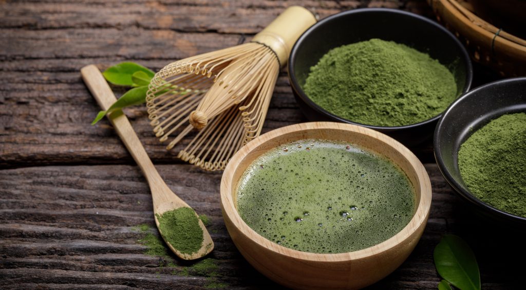 Thé matcha préparé dans un bol en bois avec chasen traditionnel, poudre de matcha de qualité cérémoniale et accessoires sur fond rustique - préparation authentique japonaise